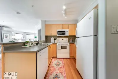 a kitchen with a white refrigerator and wooden cabinets at The Breakfast Club Suite - KingBed& AC - Patio - UG Park in Edmonton