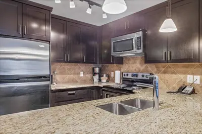 a kitchen with wooden cabinets and a stainless steel refrigerator at Peaceful 1BR Condo with Hot Tub and Pool in Canmore
