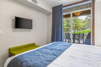 a bedroom with a bed and a flat screen tv at Peaceful 1BR Condo with Hot Tub and Pool in Canmore