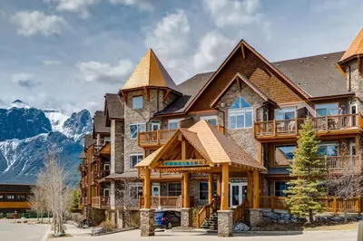 a large house with mountains in the background at Peaceful 1BR Condo with Hot Tub and Pool in Canmore