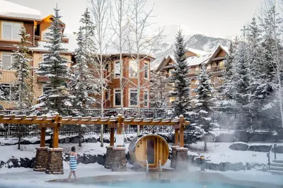 a woman standing in the snow in front of a building at Peaceful 1BR Condo with Hot Tub and Pool in Canmore