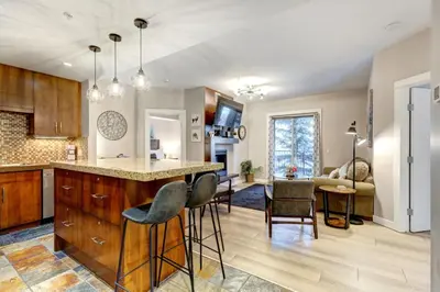 a kitchen and living room with a bar and chairs at Silver Creek 2BR Bliss Hot Tub Access MTN Views in Canmore
