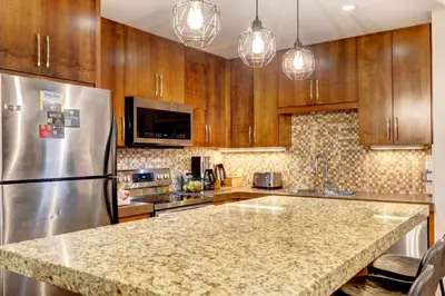 a kitchen with wooden cabinets and a stainless steel refrigerator at Silver Creek 2BR Bliss Hot Tub Access MTN Views in Canmore