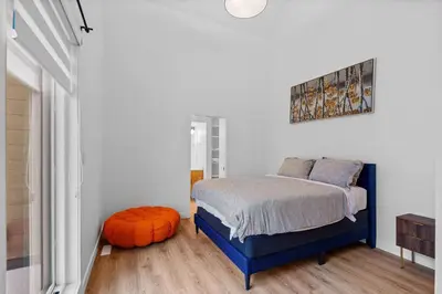 a bedroom with a blue bed and an orange ottoman at Luxurious Large 3 Bedroom Loft Saskatchewan Drive in Edmonton
