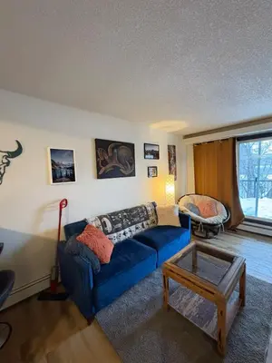 a living room with a blue couch and a table at Cozy boho downtown apartment in Calgary