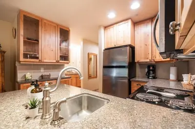 a kitchen with a sink and a stainless steel refrigerator at Wildwood Lodge 113 by Outpost Whistler in Whistler