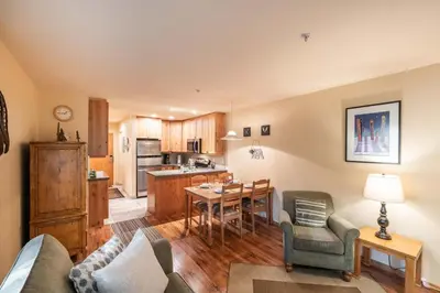 a living room with a couch and a table and a kitchen at Wildwood Lodge 113 by Outpost Whistler in Whistler