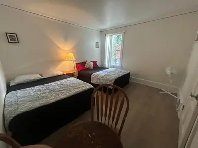 a room with two beds and a chair and a window at Vancouver Budget Guesthouse - Free Parking, Fast WiFi, Near Airport & Downtown in Vancouver