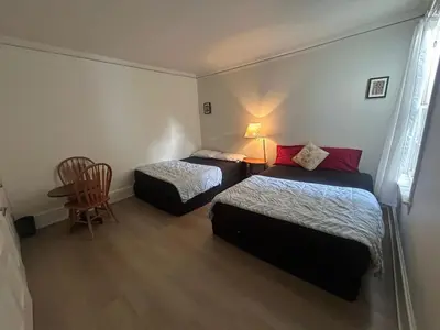 a room with two beds and a table and a chair at Vancouver Budget Guesthouse - Free Parking, Fast WiFi, Near Airport & Downtown in Vancouver