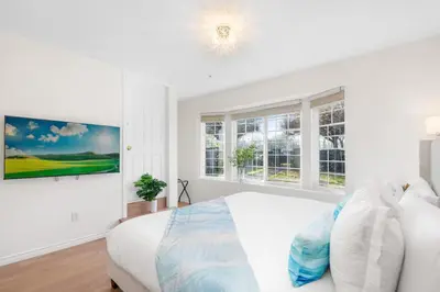 a white bedroom with a large bed and windows at NEW Roomy 3BR Family Suite. 5 min to Skytrain. in Vancouver