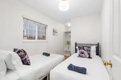two beds in a room with white walls and a window at NEW Roomy 3BR Family Suite. 5 min to Skytrain. in Vancouver