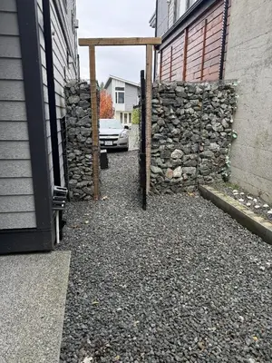 a stone wall next to a building with a car at Ridge Pointe Retreat Your Victoria Hideaway in Colwood
