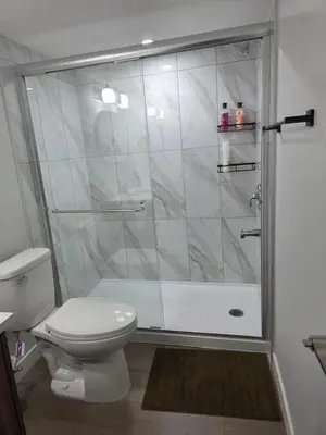 a bathroom with a toilet and a glass shower at YYC Cozy Suites in Calgary