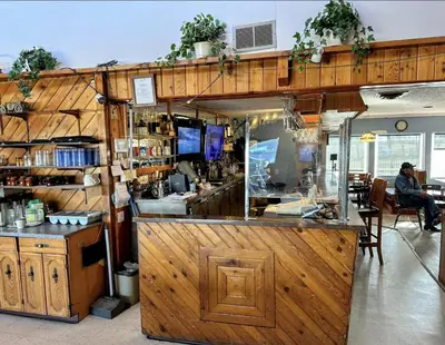 a bar in a restaurant with a person sitting at a table at Country Road Motor Inn