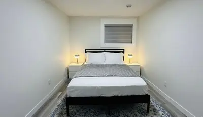 a white bedroom with a bed and two lamps at Brand New cozy apartment bright, modern private 2 bedroom basement! in Calgary