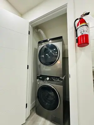 a washer and dryer in a laundry room with a red light at Brand New cozy apartment bright, modern private 2 bedroom basement! in Calgary