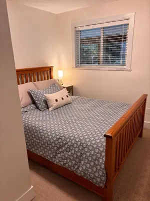a bedroom with a bed with a wooden frame and a window at Sumas Mountain basement suite in Abbotsford