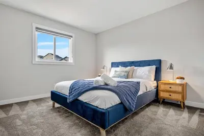 a bedroom with a blue bed and a window at Herron Rise Luxury 4 Bedroom Main Floor in Calgary