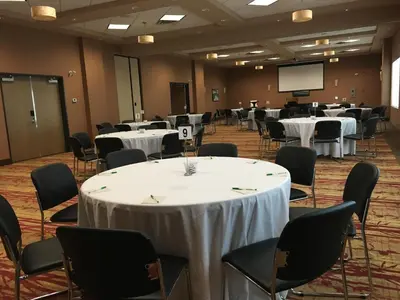 a conference room with tables and chairs and a screen at Hotel 11, MOD A Sonesta Collection in Calgary
