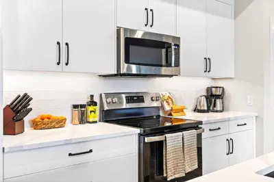 a white kitchen with a stove and a microwave at Tranquil 2BR Golden Oasis BBQ, Balcony, MTN Views in Golden