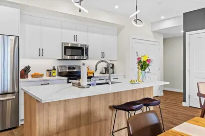 a kitchen with white cabinets and a counter with stools at Tranquil 2BR Golden Oasis BBQ, Balcony, MTN Views in Golden