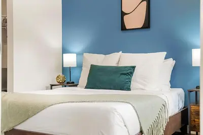 a blue bedroom with a bed with a green pillow at Brand New 2BR Oasis Mins to DT with AC Balcony and BBQ in Golden