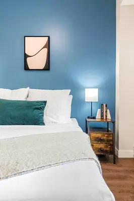 a blue bedroom with a bed and a side table at Brand New 2BR Oasis Mins to DT with AC Balcony and BBQ in Golden