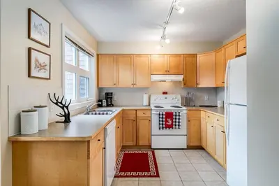 a kitchen with wooden cabinets and a white refrigerator at Cozy 2 BR Condo plus Gym with Stunning Mountain View in Canmore