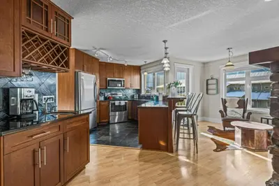 a large kitchen with wooden cabinets and a table at Mountain View Retreat Elegant 3BR condo with Gym in Canmore