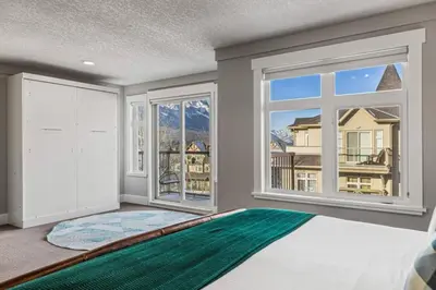 a room with a large window and a green rug at Mountain View Retreat Elegant 3BR condo with Gym in Canmore
