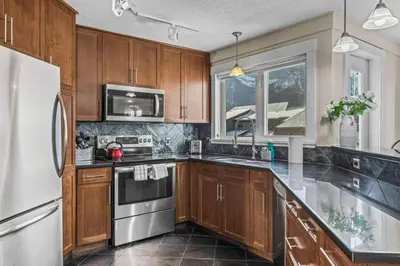 a kitchen with wooden cabinets and stainless steel appliances at Mountain View Retreat Elegant 3BR condo with Gym in Canmore
