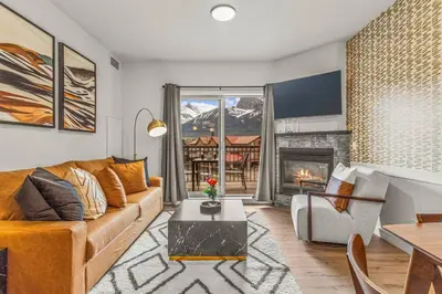a living room with a couch and a fireplace at Rockies Getaway Condo With Mountain View in Canmore