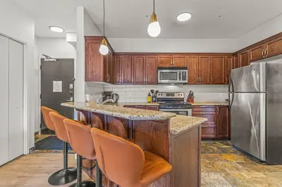 a kitchen with wooden cabinets and a stainless steel refrigerator at Rockies Getaway Condo With Mountain View in Canmore