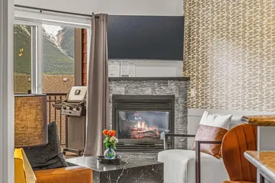 a living room with a fireplace and a couch at Rockies Getaway Condo With Mountain View in Canmore