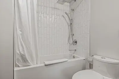 a white bathroom with a shower and a toilet at Renovated Haven in Rockies with Hot Tub and Pool in Canmore