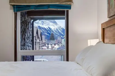 a bedroom with a view of a snowy mountain from a window at Renovated Haven in Rockies with Hot Tub and Pool in Canmore