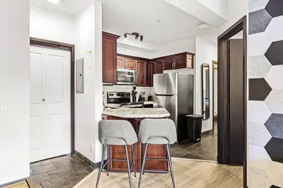a kitchen with a refrigerator and two stools at Splendid Mountain View 2BR Condo with Pool and Hot Tub in Canmore