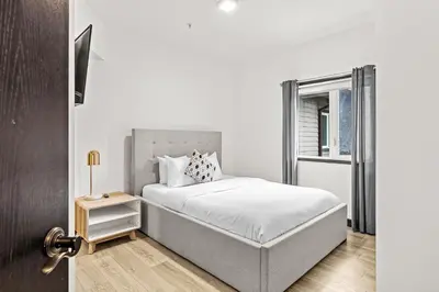 a white bedroom with a bed and a window at Splendid Mountain View 2BR Condo with Pool and Hot Tub in Canmore