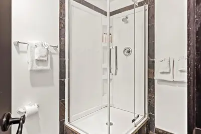a shower with a glass door in a bathroom at Splendid Mountain View 2BR Condo with Pool and Hot Tub in Canmore