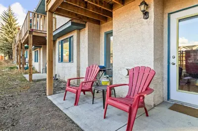 two red chairs and a table on a porch at 2BR Bow Valley Retreat with BBQ Near Parks and Banff in Canmore