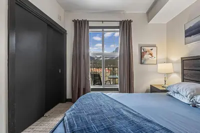 a bedroom with a bed and a large window at Relaxing 1BR Getaway Hot tub plus Amazing Mtn Views in Canmore