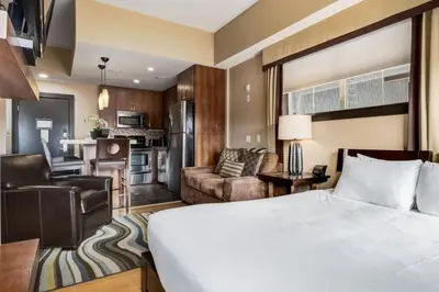 a hotel room with a bed and a living room at Cozy Rocky Mountain Studio with Hot tub and Gym in Canmore