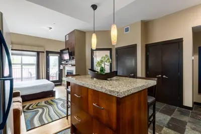 a bedroom with a bed and a kitchen with a island at Cozy Rocky Mountain Studio with Hot tub and Gym in Canmore