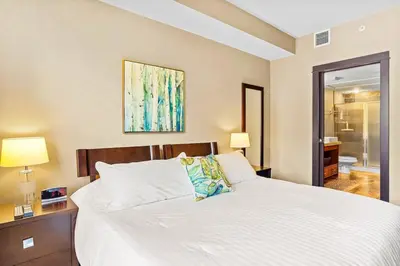 a bedroom with a large white bed and a bathroom at Ideal 2BR Canmore Haven Hot Tub plus Stunning Views in Canmore