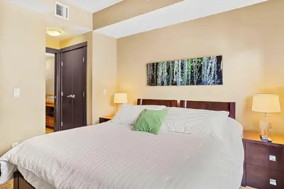 a bedroom with a large white bed with green pillows at Ideal 2BR Canmore Haven Hot Tub plus Stunning Views in Canmore