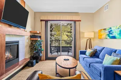 a living room with a blue couch and a fireplace at Ideal 2BR Canmore Haven Hot Tub plus Stunning Views in Canmore