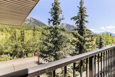 a balcony with a view of trees and mountains at Ideal 2BR Canmore Haven Hot Tub plus Stunning Views in Canmore