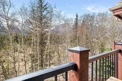 a balcony with a view of the woods at Peaceful 2BR Retreat with MTN Views Close to Banff in Canmore