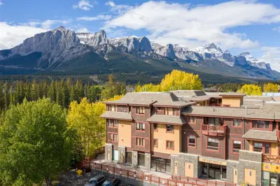 an apartment building with mountains in the background at Rustic Creekside Retreat 2BR with Stunning View in Canmore