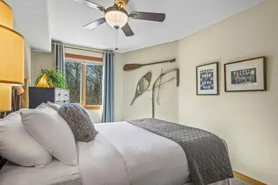 a bedroom with a white bed with a ceiling fan at Rustic Creekside Retreat 2BR with Stunning View in Canmore